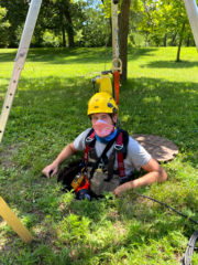 Mike with a safety harness, helmet and a mask at the entrance to an underground monitoring station 