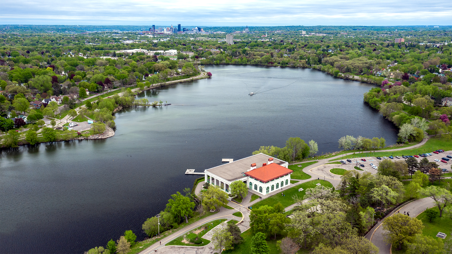 Aerial view of Como Lake and pavilion. Boat applying alum is in the center of lake with faint trails of white alum.