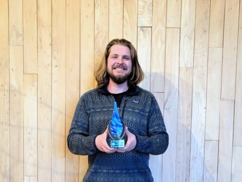 Jens Kvaal holding a blue-swirled glass raindrop award.