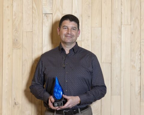 Person holding a blue-swirled glass raindrop award.